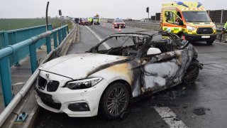Řidič dodávky přehlédl BMW stojící u krajnice dálnice. Po nehodě shořelo, jeho šofér bojuje o život